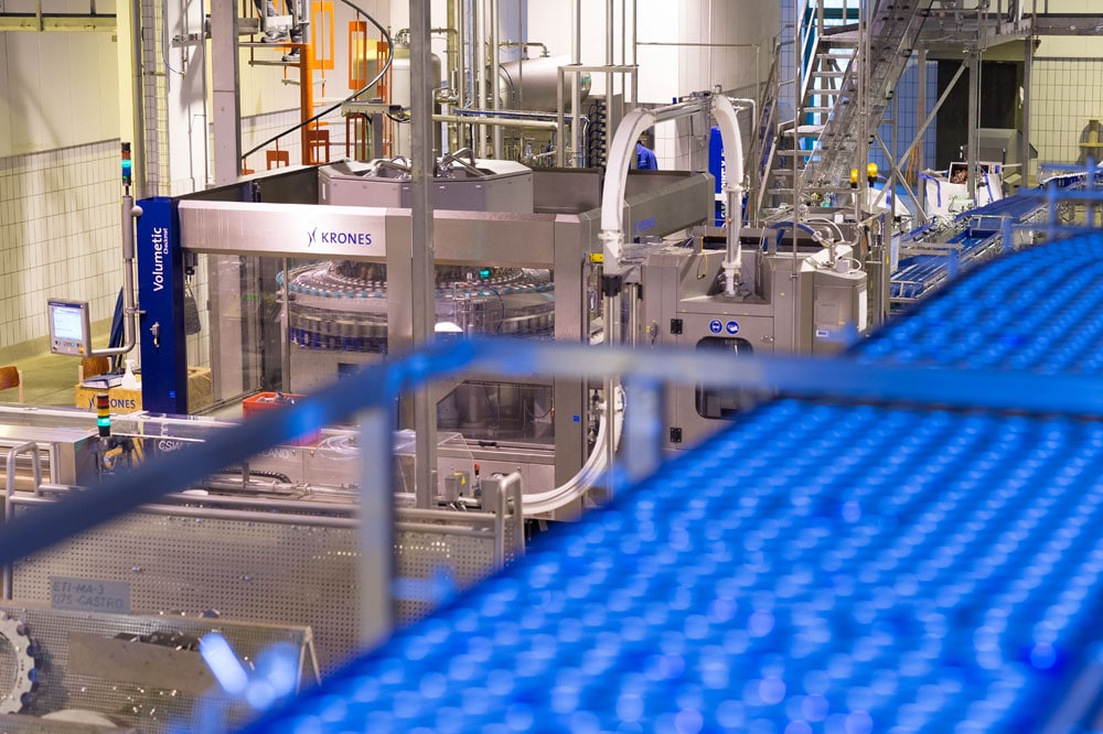Las latas son transportadas en masa y separadas antes de llegar a una enjuagadora de gravedad, en la cual descienden a la altura del nivel de la llenadora mientras son enjuagadas.